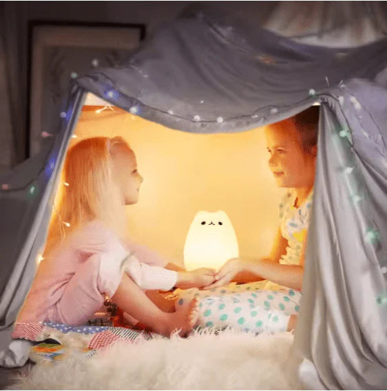 Two girls enjoying a cozy indoor tent with a glowing squishy animal lamp illuminating their playtime